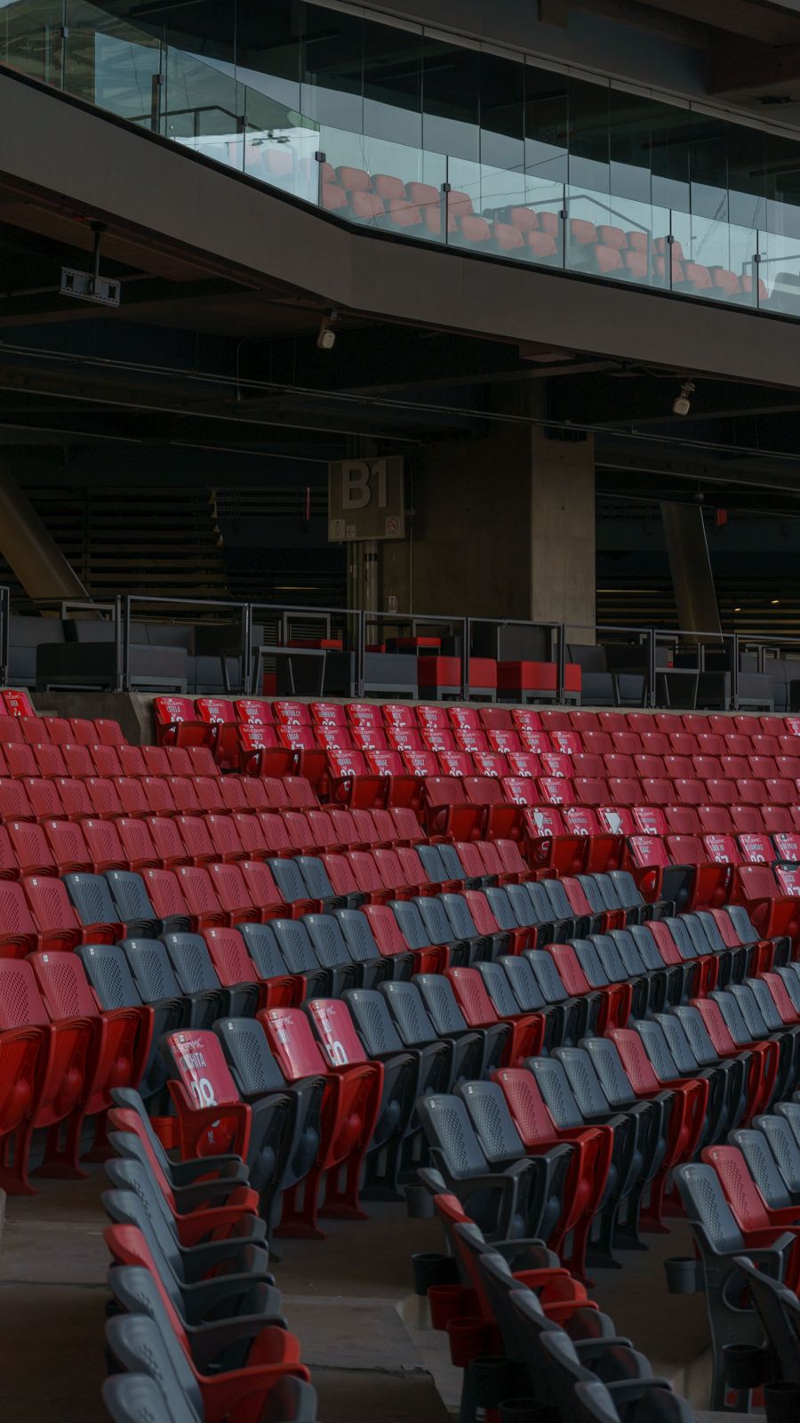 Rows of red stadium seats below a glass suite level